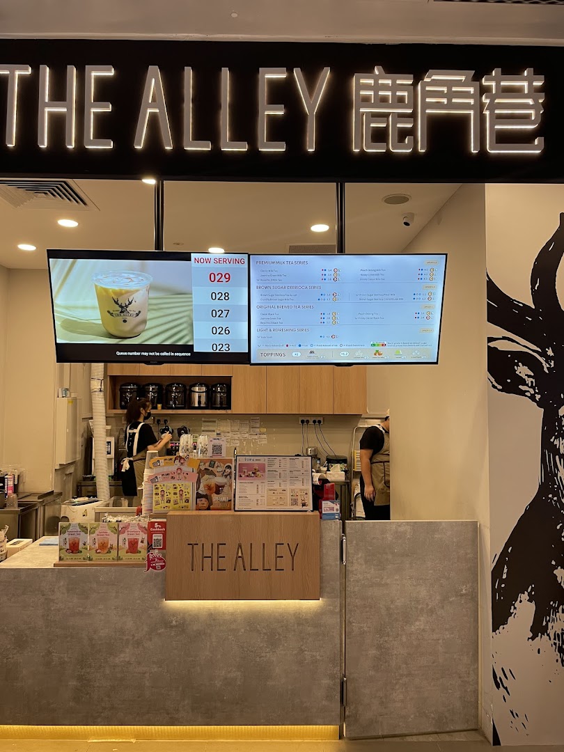 Interior view of The Alley bubble tea shop, featuring the service counter, digital menu boards, and staff.