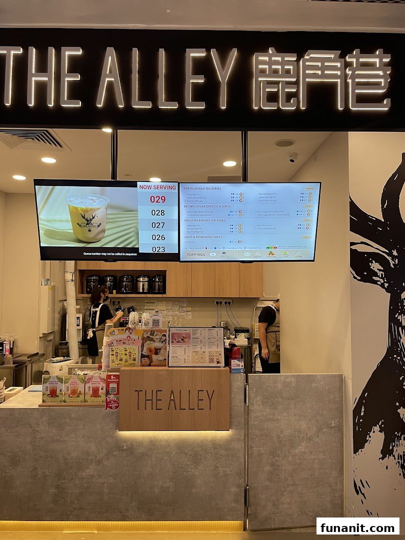 Interior view of The Alley bubble tea shop, featuring the service counter, digital menu boards, and staff.