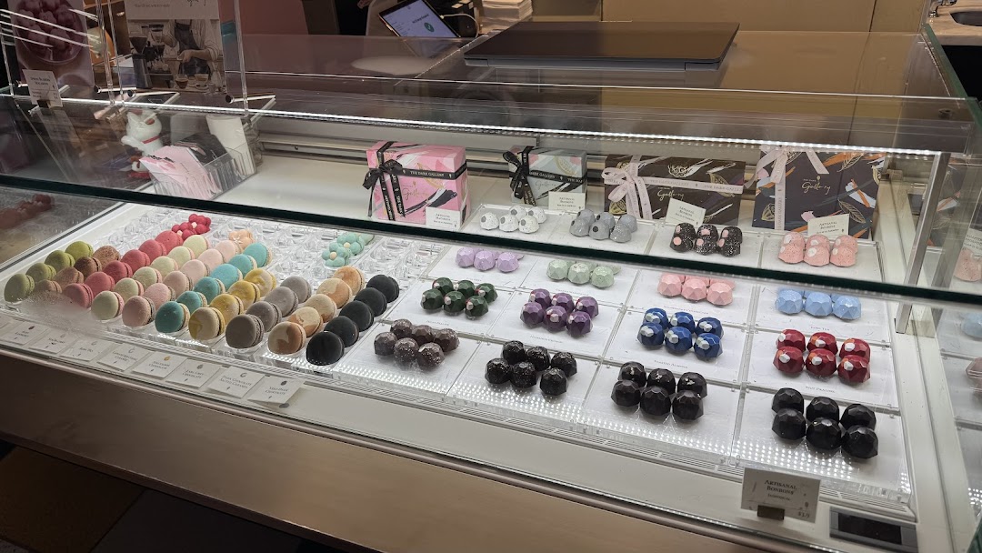 A vibrant display case showcasing an array of colorful macarons and artisanal chocolates.