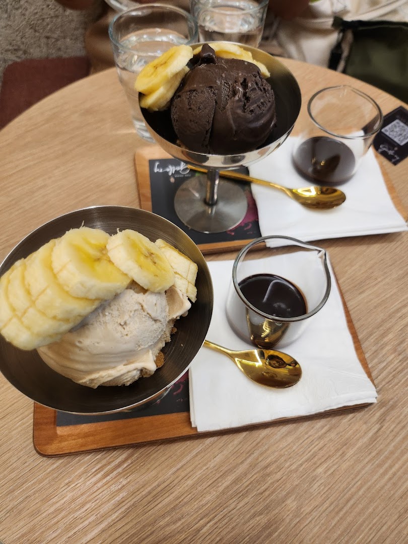 Two delicious ice cream sundaes with banana slices and chocolate sauce on a wooden table.