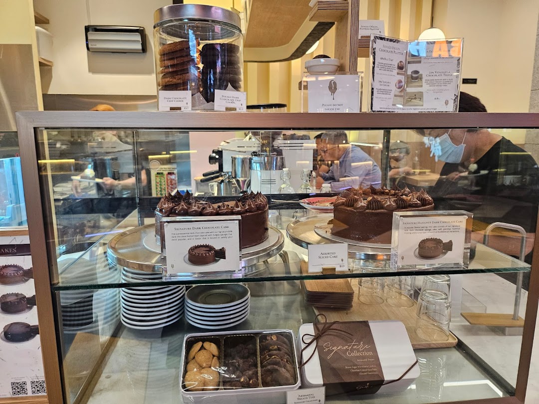 A display case showcasing decadent chocolate cakes, cookies, and treats at The Dark Gallery.