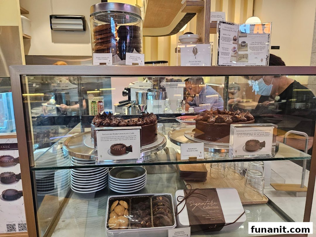A display case showcasing decadent chocolate cakes, cookies, and treats at The Dark Gallery.