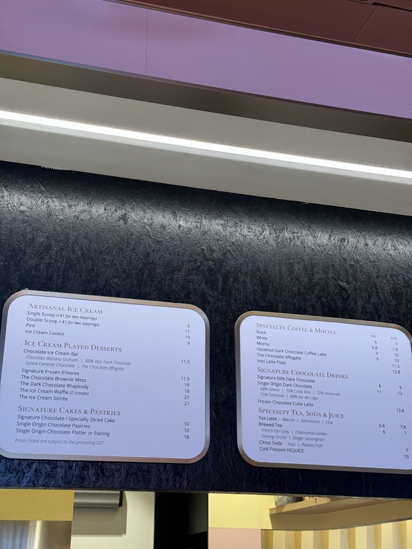 A detailed menu board displaying artisanal ice cream, plated desserts, cakes, pastries, coffee, chocolate drinks, teas, sodas, and juices.