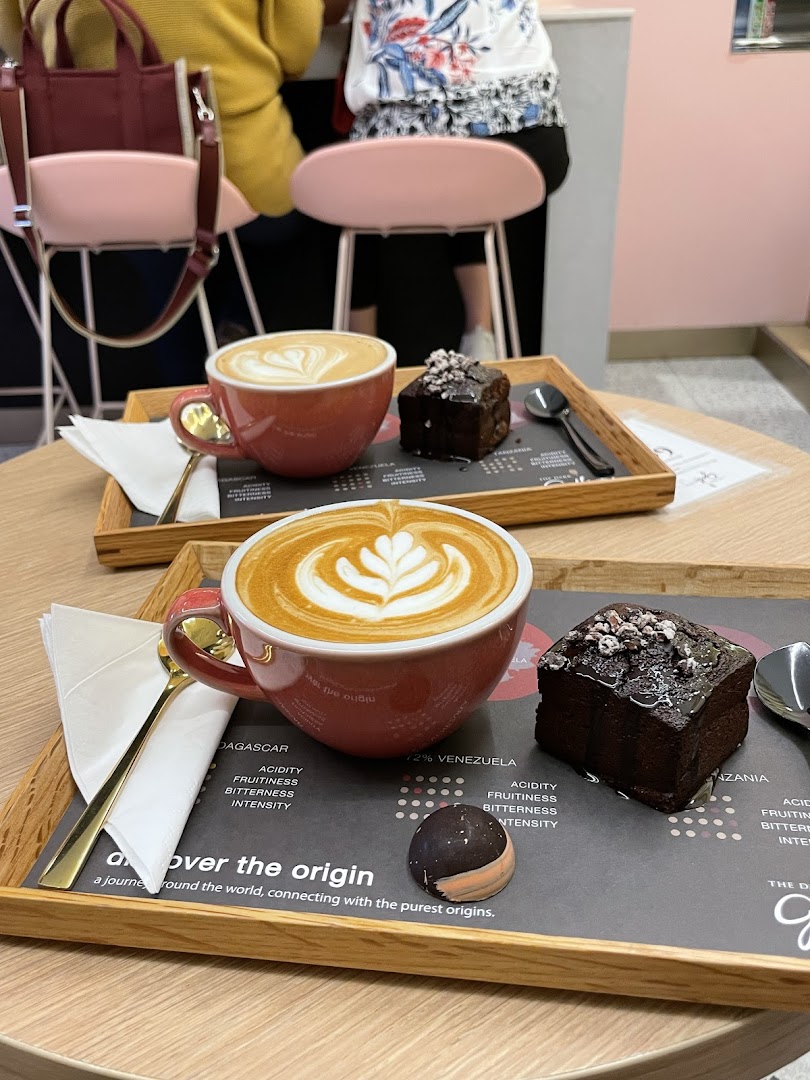 Two beautifully crafted lattes and chocolate desserts served on wooden trays.