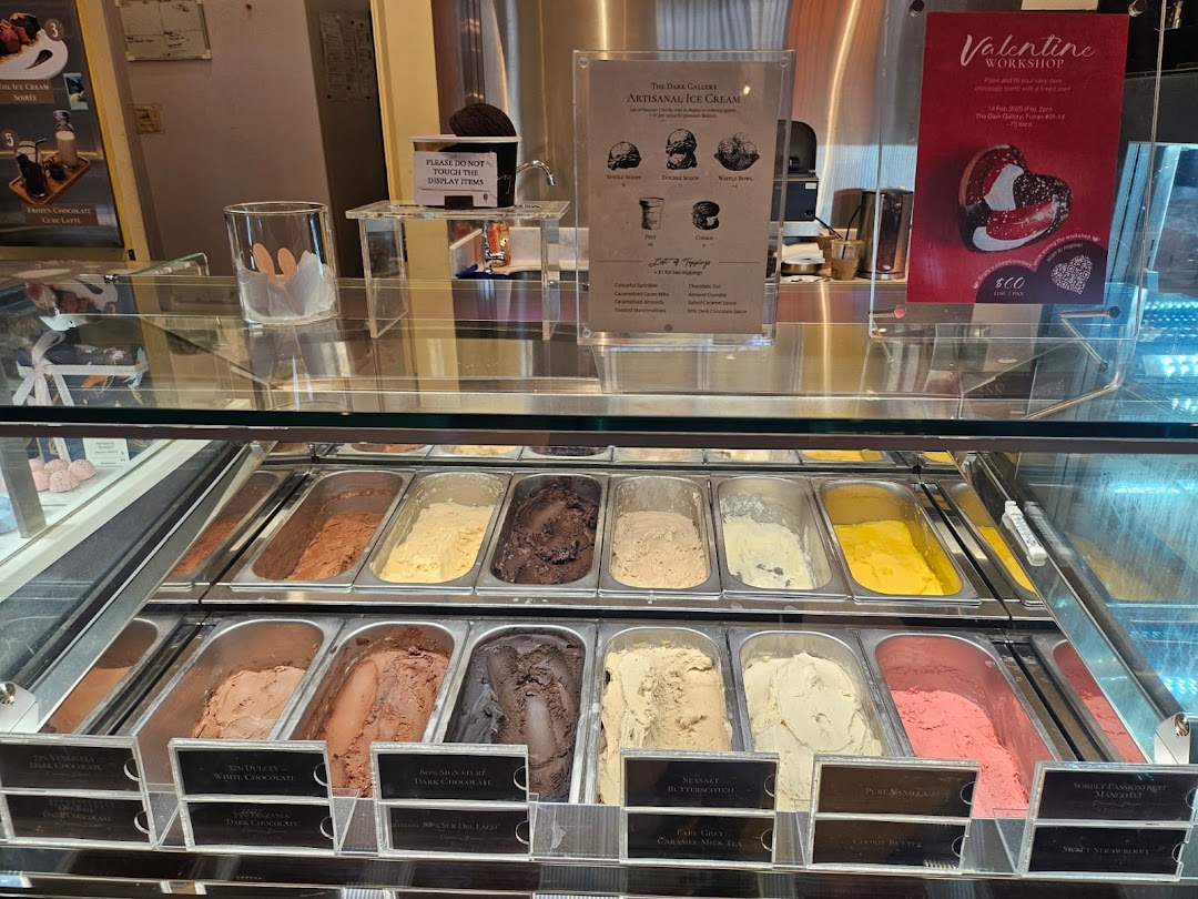 A vibrant display of artisanal ice cream flavors in a glass freezer at The Dark Gallery.