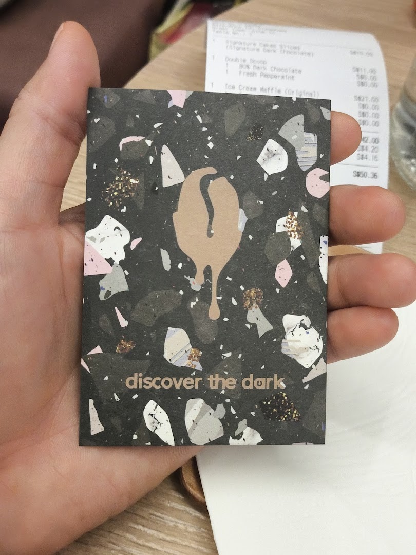 A hand holds a "discover the dark" card with a chocolate-themed design.