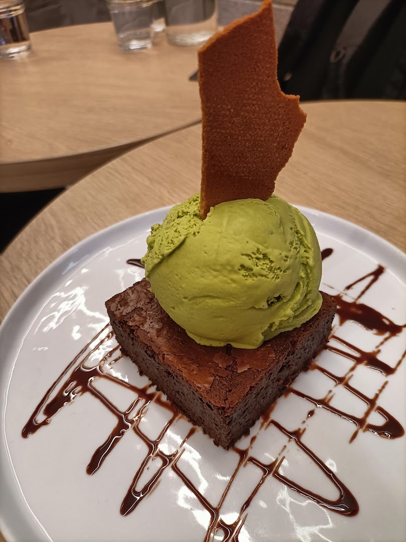 A rich chocolate brownie topped with a scoop of green ice cream and a crisp wafer.