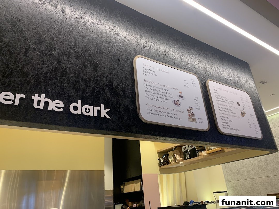 A close-up view of The Dark Gallery's menu boards displaying artisanal ice cream, plated desserts, and chocolate drinks.