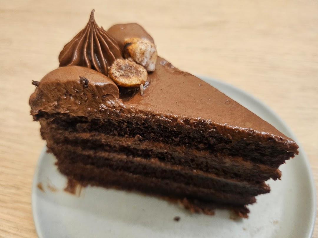 A decadent slice of multi-layered chocolate cake with rich frosting and nuts.