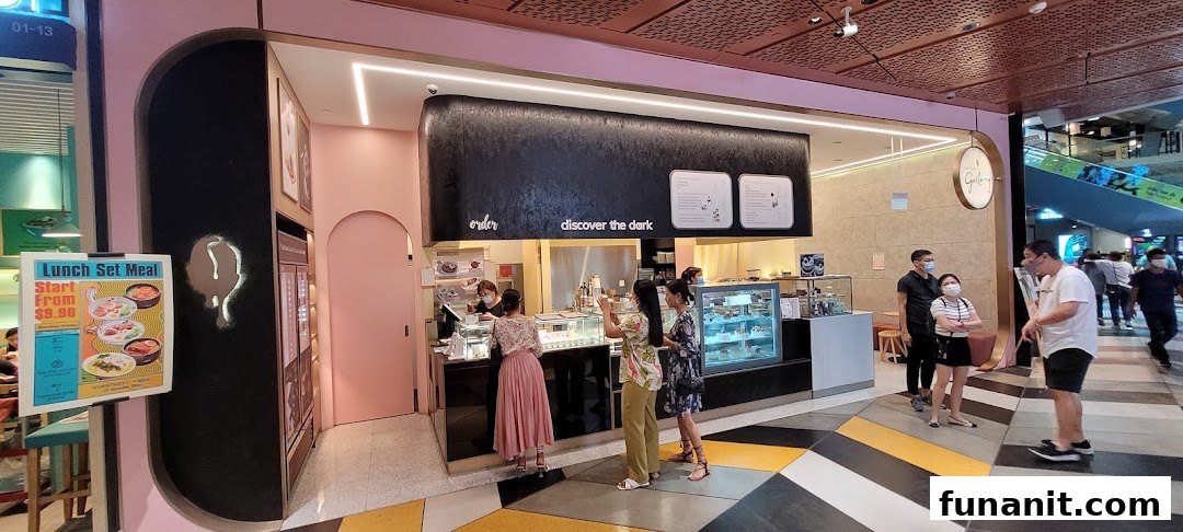 Customers interact with staff and browse desserts at The Dark Gallery, a chocolate-themed cafe.