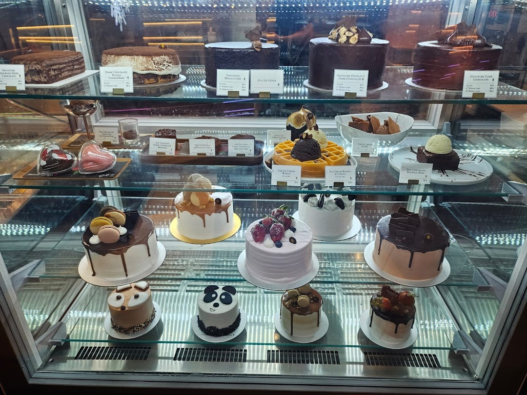 A display case showcasing a variety of decadent chocolate cakes, pastries, and desserts.