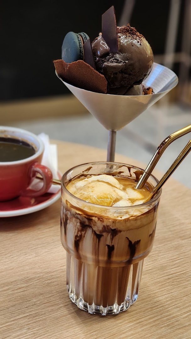A decadent chocolate dessert, an iced coffee with ice cream, and a hot coffee on a wooden table.