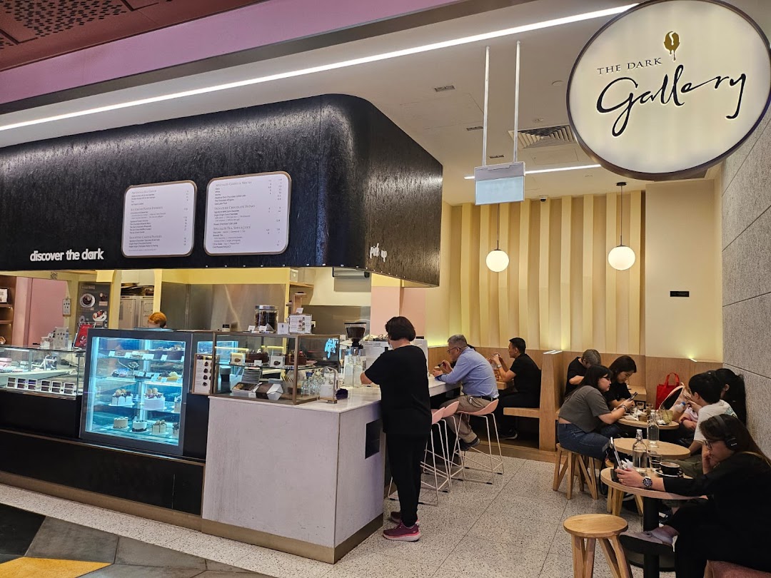 Interior view of The Dark Gallery, showcasing menu boards, display cases, and customers.