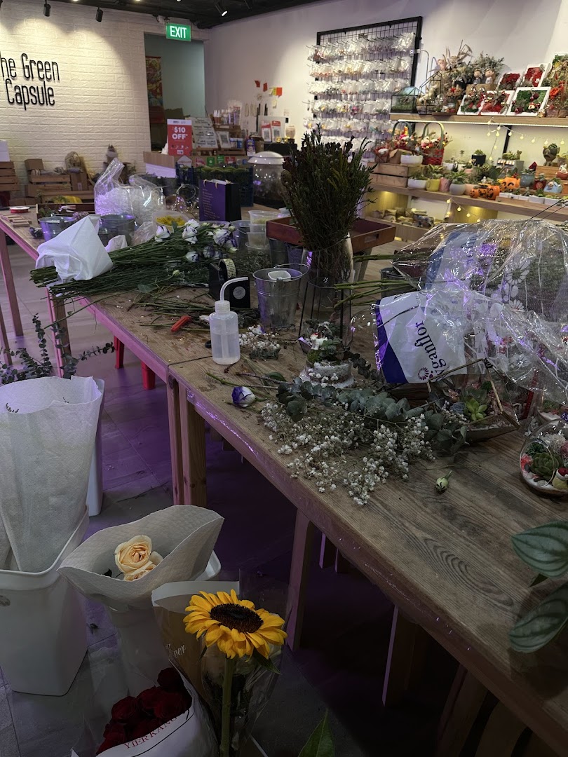 An active workspace inside The Green Capsule, featuring flowers, tools, and botanical products.