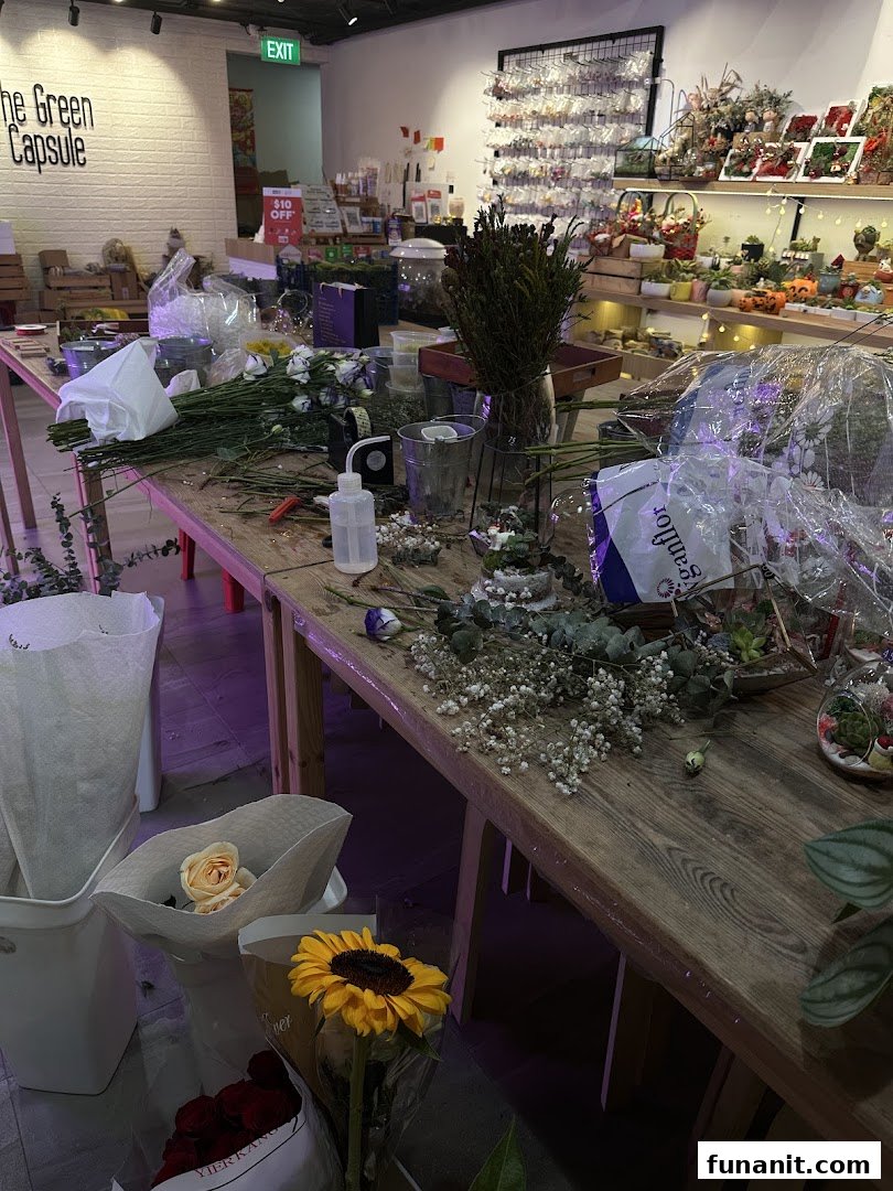 An active workspace inside The Green Capsule, featuring flowers, tools, and botanical products.