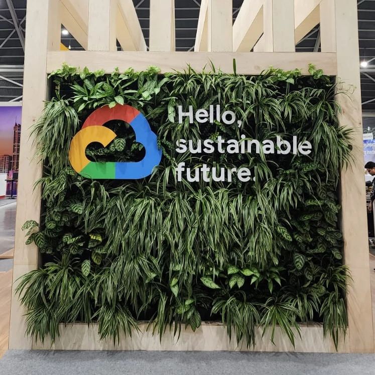 A lush vertical garden display promoting sustainability, featuring a cloud logo and inspiring text.