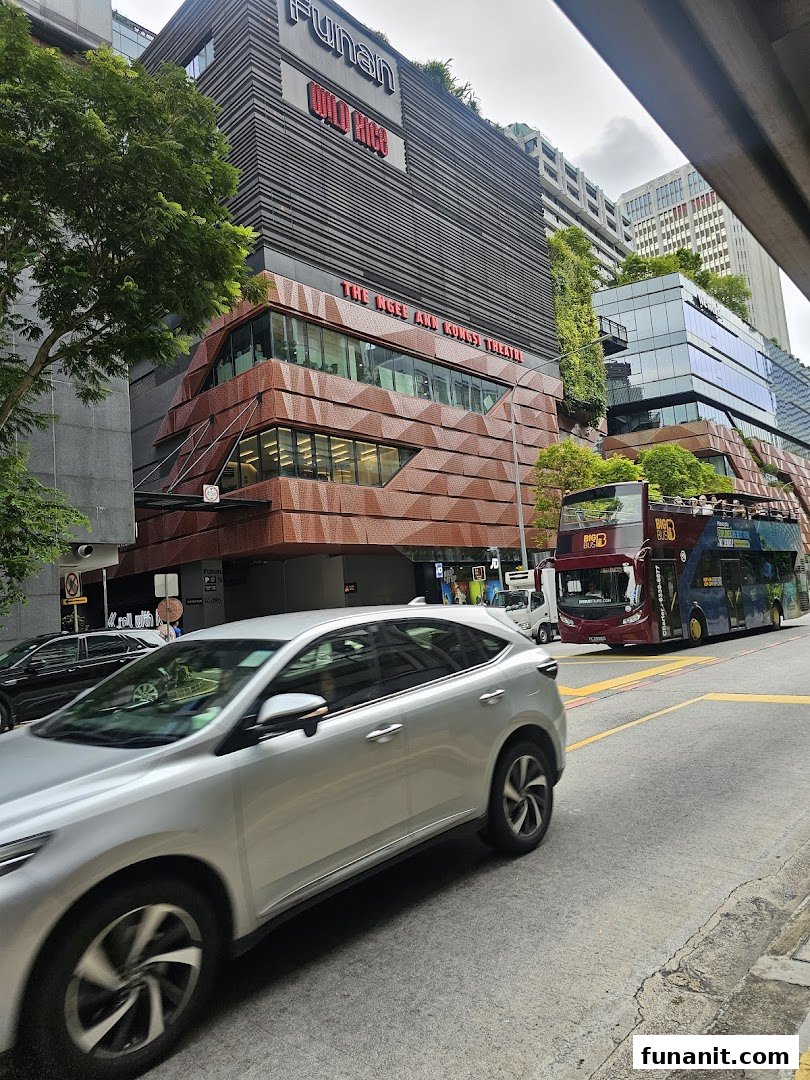 Exterior view of The Ngee Ann Kongsi Theatre at Funan mall, featuring modern architecture and street activity.