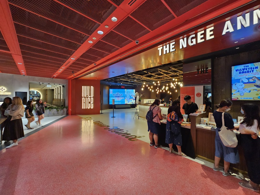 The Ngee Ann Kongsi Theatre lobby with red decor, people at a counter, and event signage.