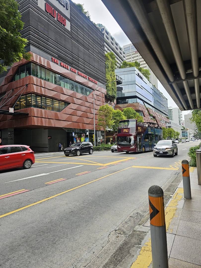 Exterior view of The Ngee Ann Kongsi Theatre building with street traffic and lush greenery.