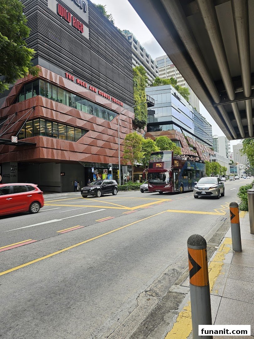 Exterior view of The Ngee Ann Kongsi Theatre building with street traffic and lush greenery.
