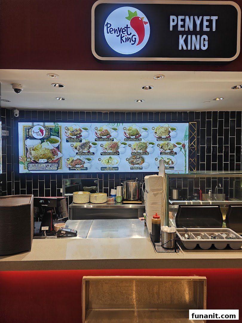 A food stall counter featuring a large digital menu board with various Indonesian 'Penyet' dishes.