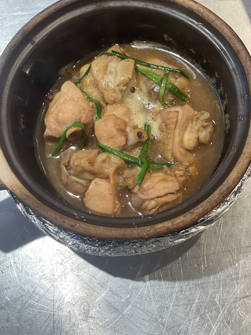 A close-up of a delicious claypot chicken dish with gravy and spring onions.