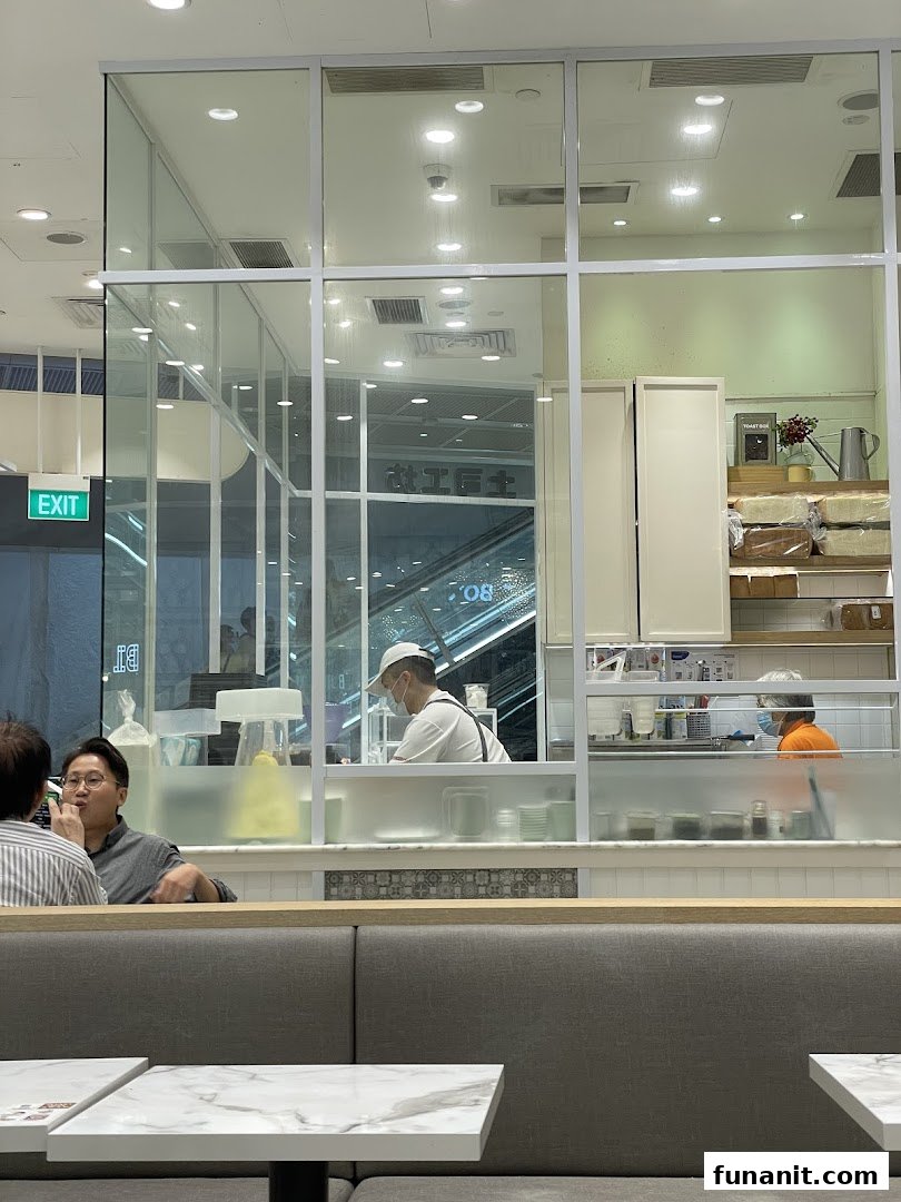Interior view of Toast Box showing customers, staff, and the open kitchen area.