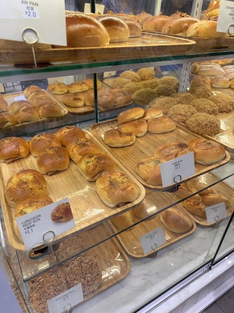A glass display case showcasing a variety of freshly baked buns and pastries at Toast Box.