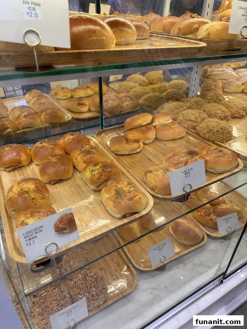 A glass display case showcasing a variety of freshly baked buns and pastries at Toast Box.