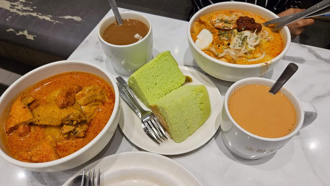 A table laden with delicious curry, laksa, pandan cake, and beverages at Toast Box.