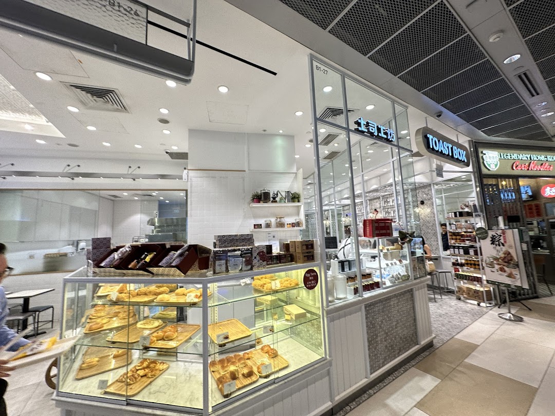 The image captures the inviting shop front of Toast Box, showcasing display cases filled with pastries and baked goods.