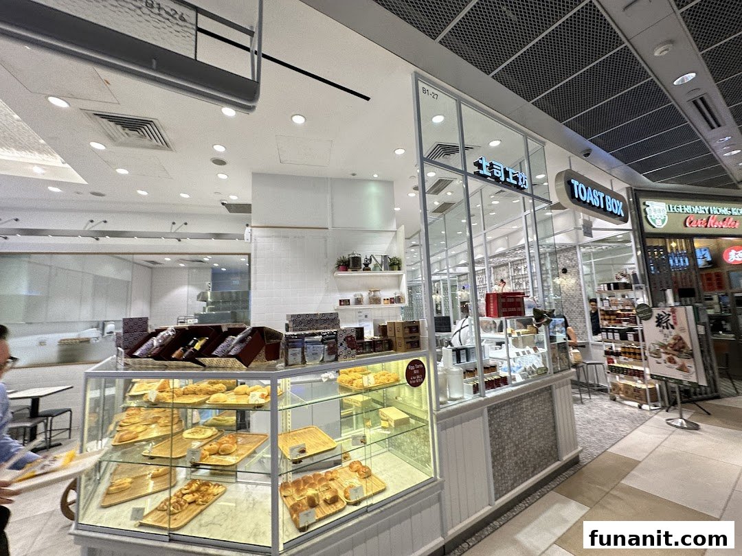 The image captures the inviting shop front of Toast Box, showcasing display cases filled with pastries and baked goods.