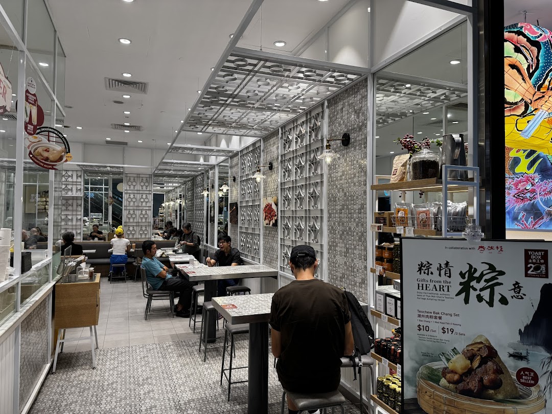 An interior view of Toast Box Funan, showing customers, seating, and a promotional display.