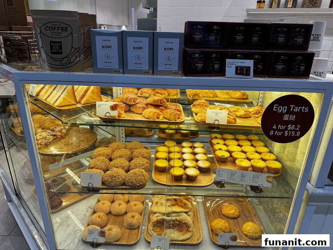 A display case at Toast Box showcasing a variety of freshly baked pastries, breads, and packaged coffee products.