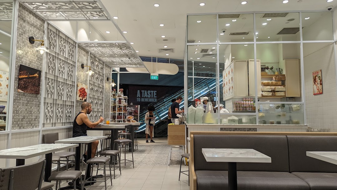 Interior view of Toast Box Funan showing seating, the service counter, and customers.