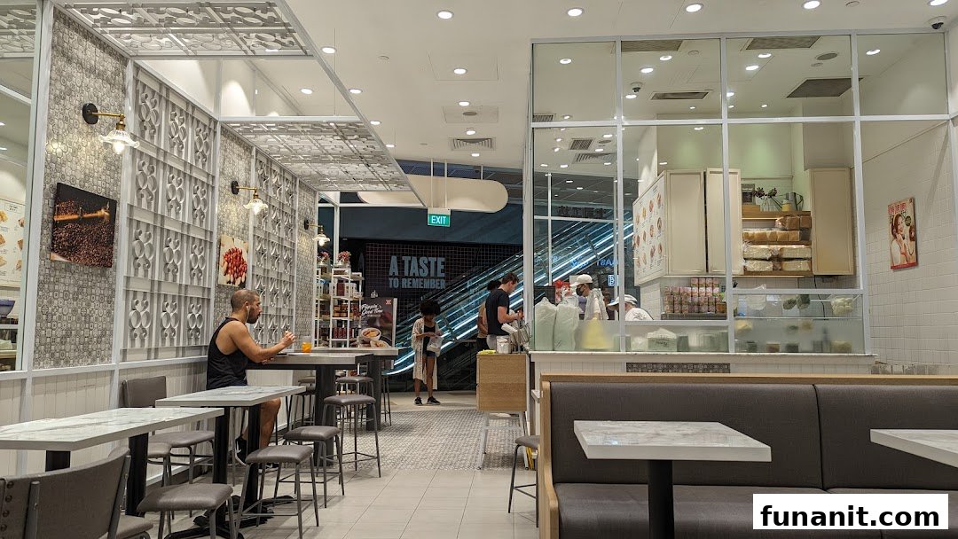 Interior view of Toast Box Funan showing seating, the service counter, and customers.