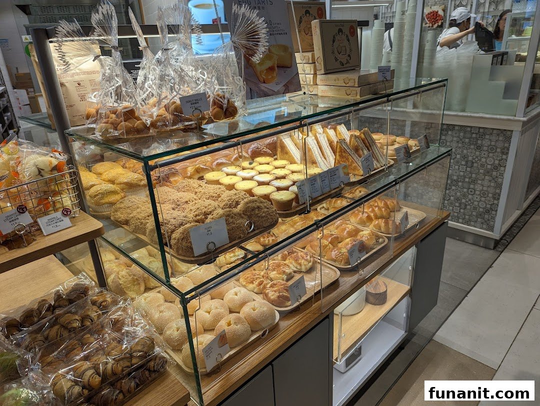 A glass display case showcasing a variety of freshly baked pastries, buns, and sandwiches at Toast Box.