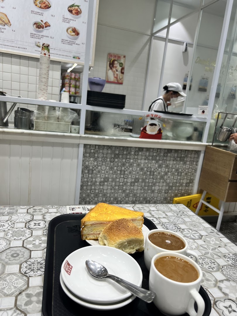 A tray with toast, a bun, and two cups of coffee on a patterned table inside Toast Box.