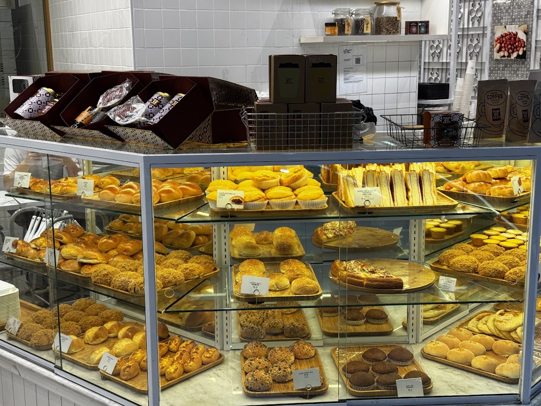 A vibrant display case showcasing a wide variety of freshly baked pastries, buns, and sandwiches at Toast Box.