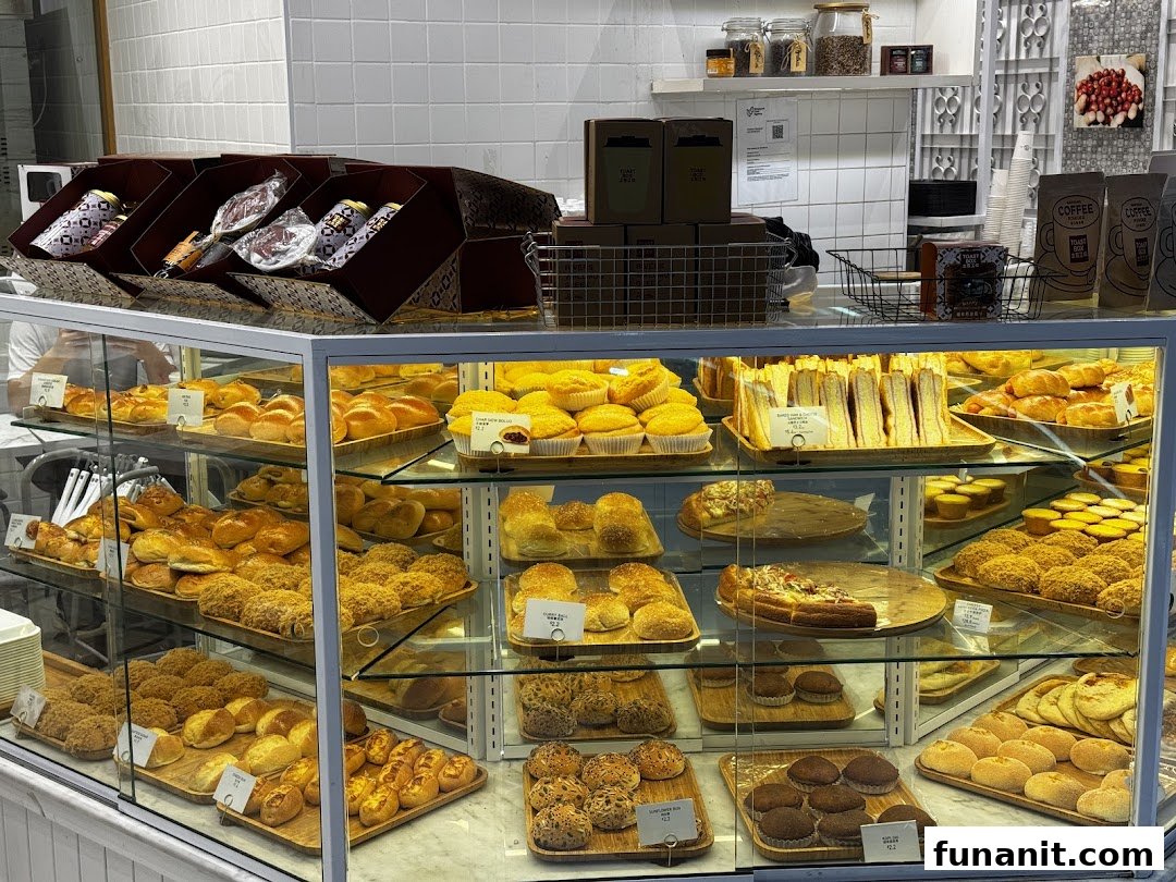 A vibrant display case showcasing a wide variety of freshly baked pastries, buns, and sandwiches at Toast Box.