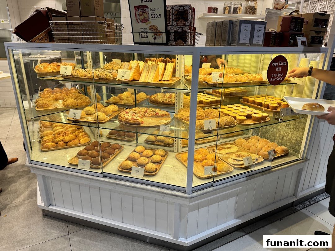 A vibrant display case showcasing a variety of freshly baked pastries, breads, and egg tarts at Toast Box.