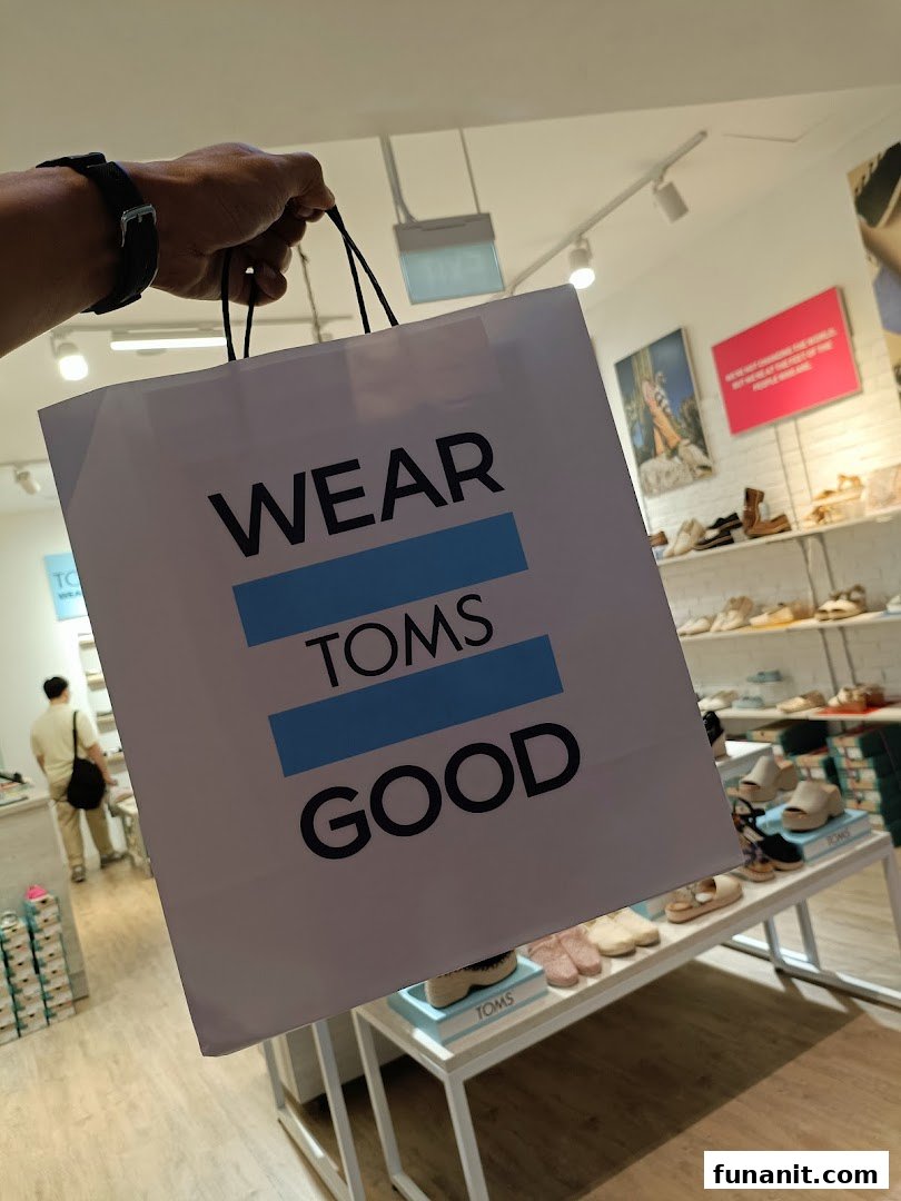 A person holds a TOMS shopping bag inside the store, showcasing the brand's message.