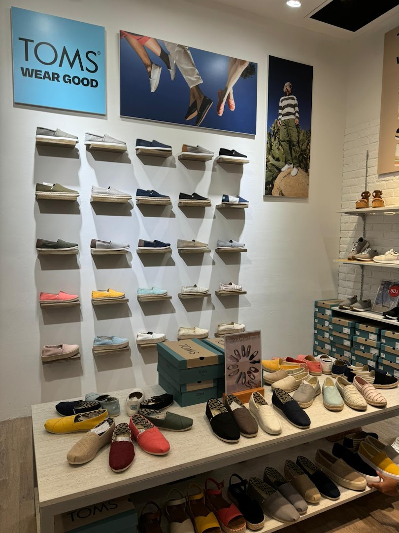 A vibrant display of various TOMS shoes on shelves and tables inside the Funan store.