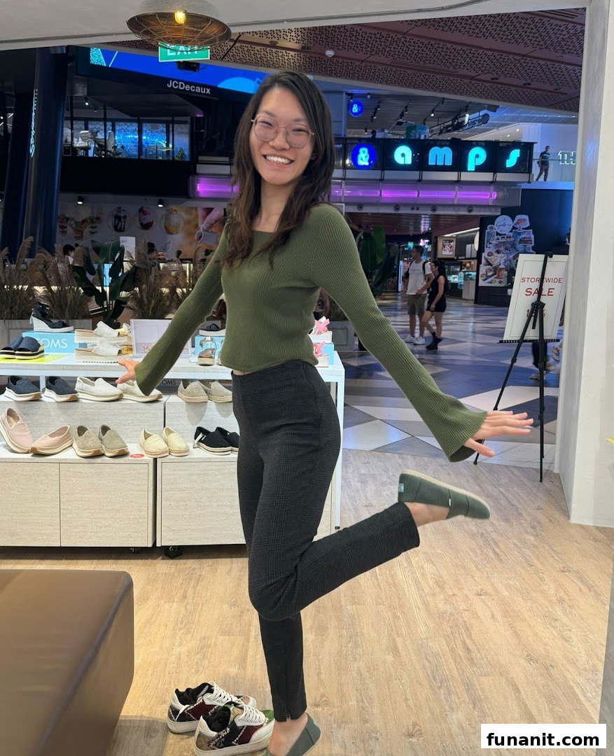 A woman playfully poses inside Toms shoe store, surrounded by various shoe displays.