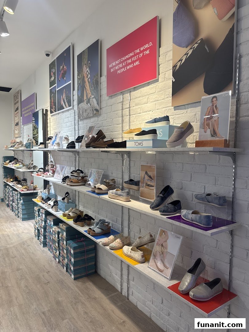 Interior view of Toms Funan showcasing various shoes on display shelves against a white brick wall.