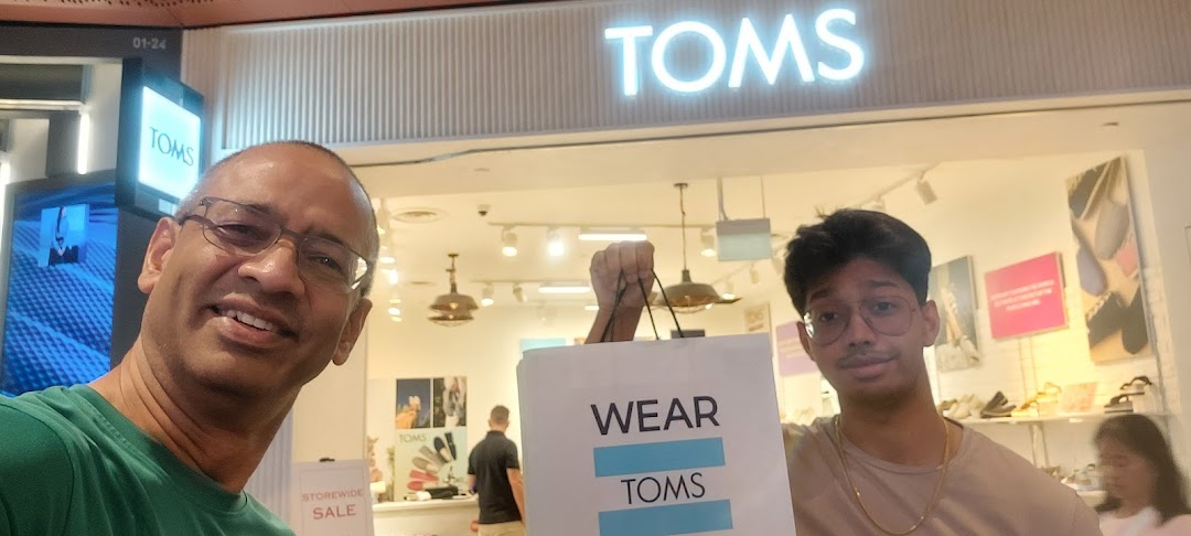 Two happy shoppers pose with their new TOMS bag in front of the TOMS store at Funan.