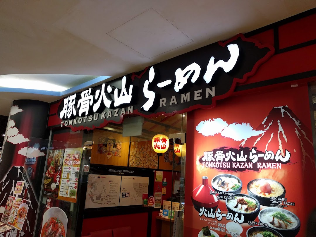 The vibrant red and black storefront of Tonkotsu Kazan Ramen, featuring its illuminated sign and menu displays.
