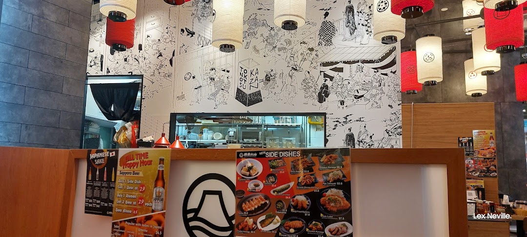 Interior view of Tonkotsu Kazan Ramen, showcasing traditional Japanese decor, an open kitchen, and promotional displays.