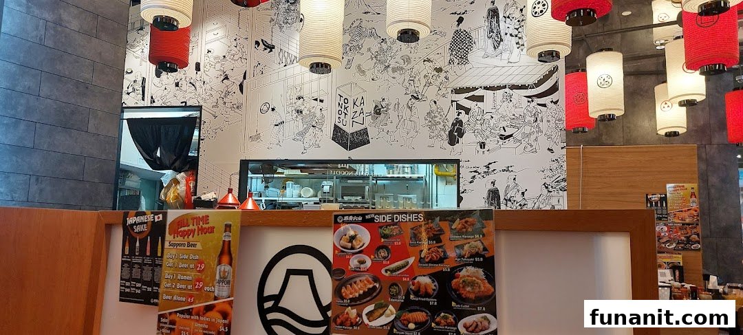 Interior view of Tonkotsu Kazan Ramen, showcasing traditional Japanese decor, an open kitchen, and promotional displays.