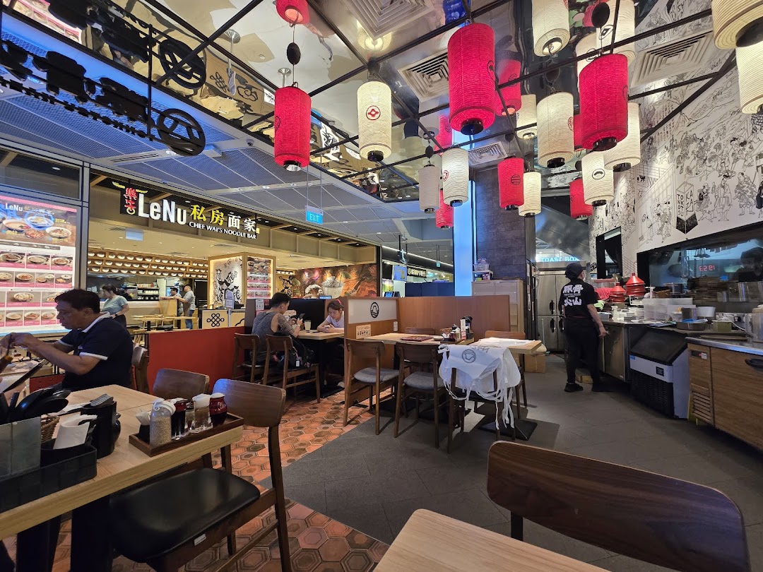 An inviting interior view of a ramen restaurant, featuring traditional lanterns, customers dining, and an open kitchen.